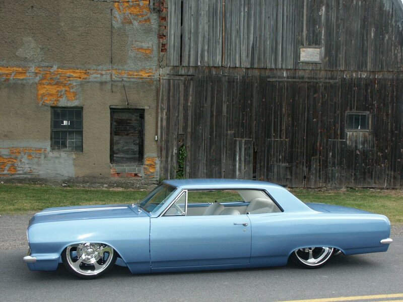 blue classic car in front of barn