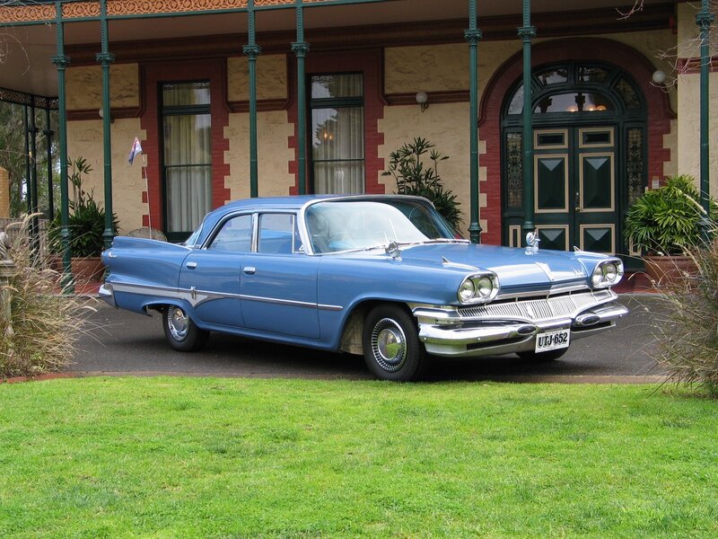 Blue classic car in front of house