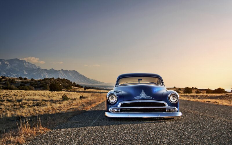 Blue classic car on a desert road