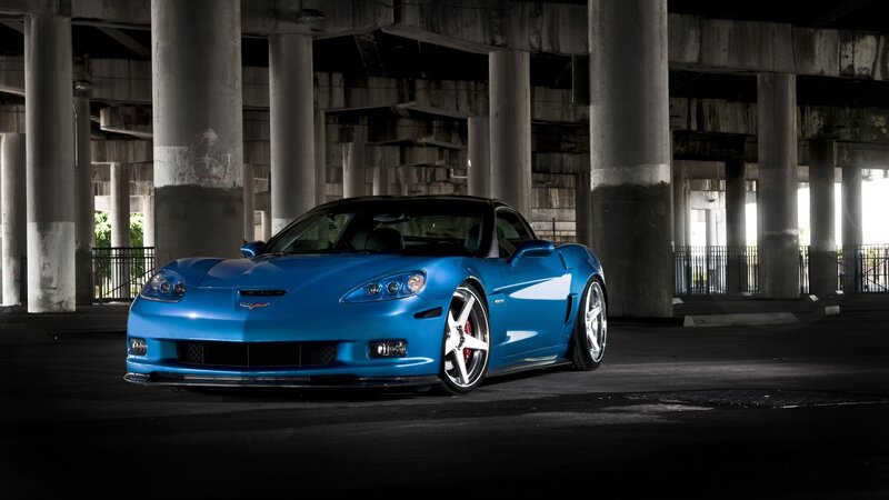 Blue Corvette under a bridge