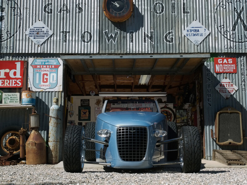 Blue custom car in front of garage