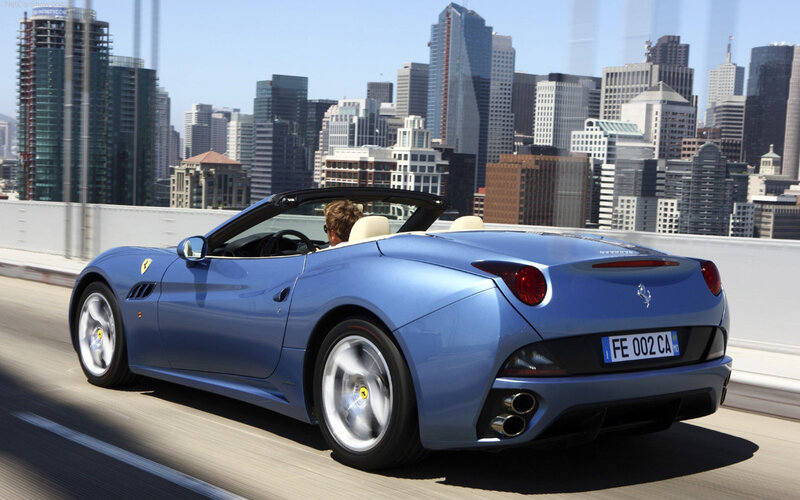 Blue Ferrari convertible on city bridge