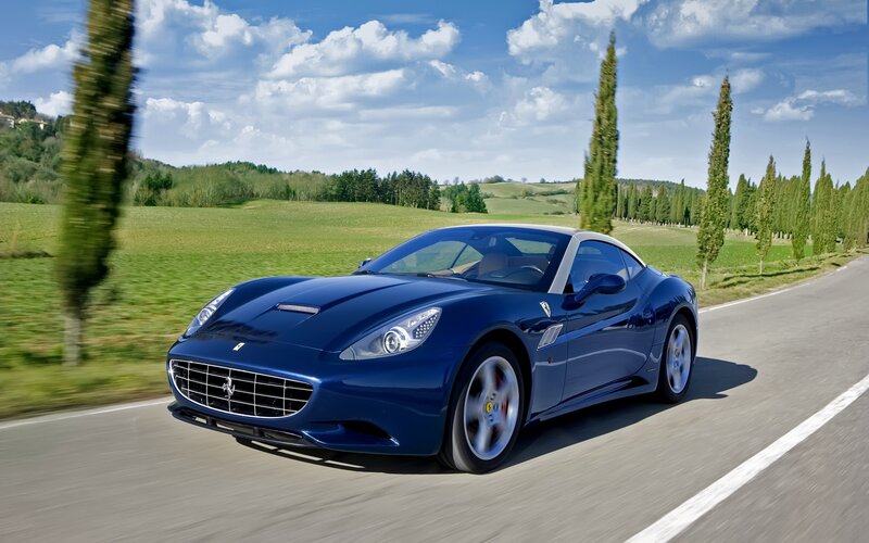 Blue Ferrari driving on a country road