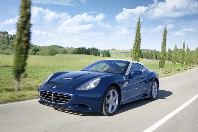 Blue Ferrari driving on a country road