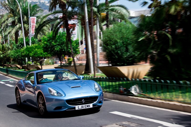 Blue Ferrari driving on a tropical road