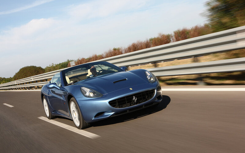 blue ferrari driving on road