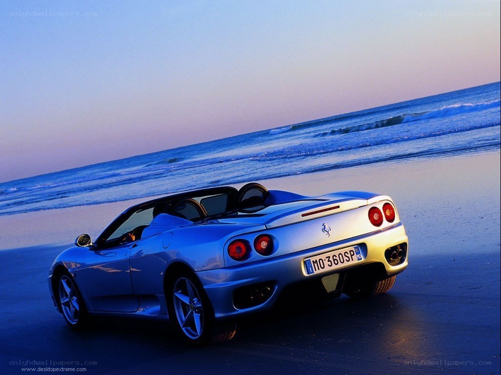Blue Ferrari on beach at sunset