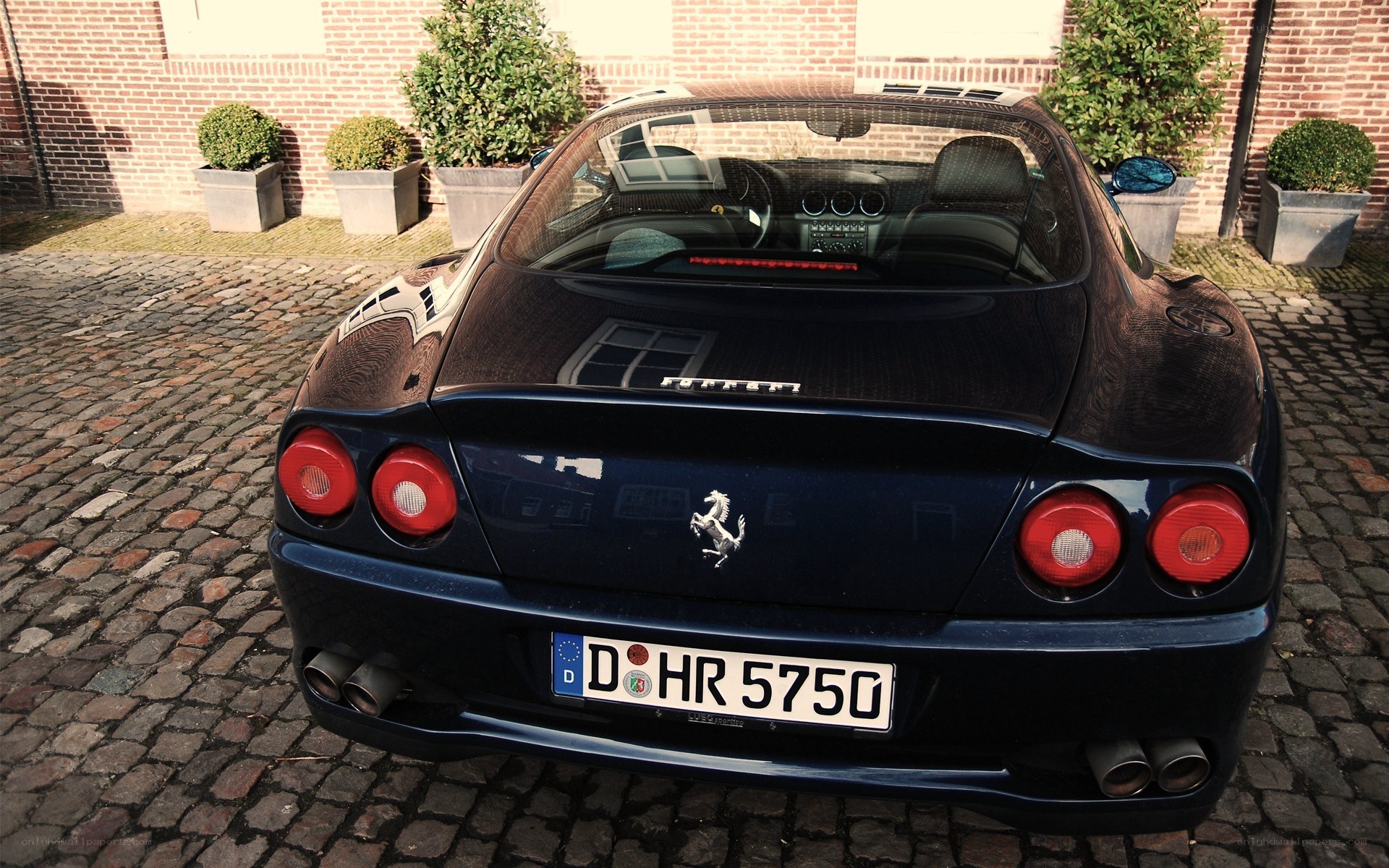 blue ferrari parked on cobblestones