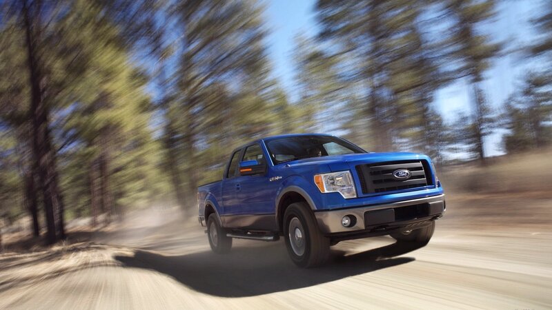 Blue Ford F-150 driving on dirt road