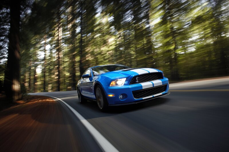 Blue Ford Mustang Shelby driving on forest road