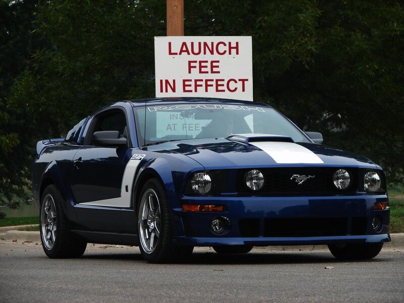 Blue Ford Mustang with launch fee sign