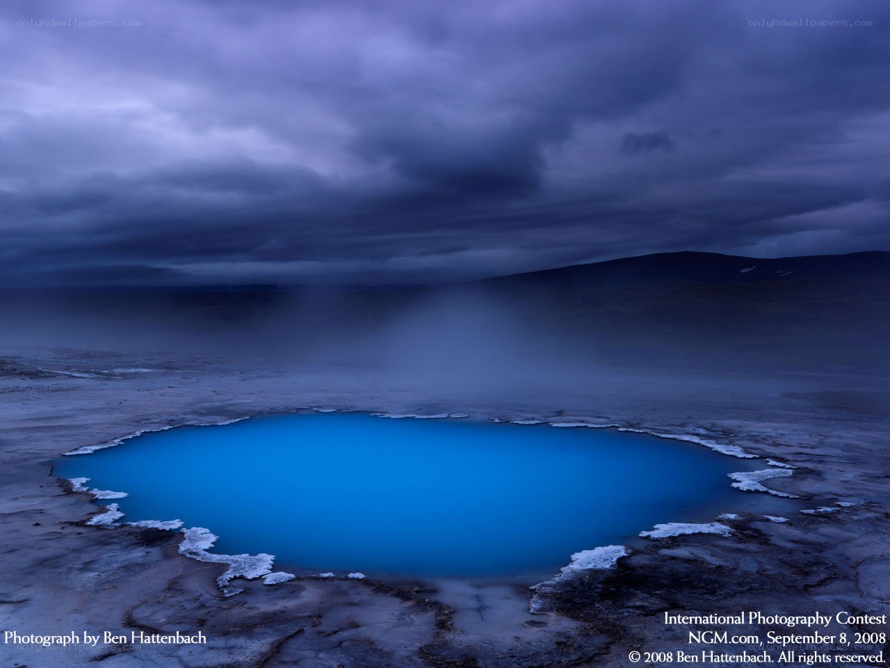 Blue geothermal pool under stormy sky