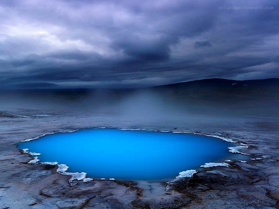 Blue geothermal pool under stormy sky