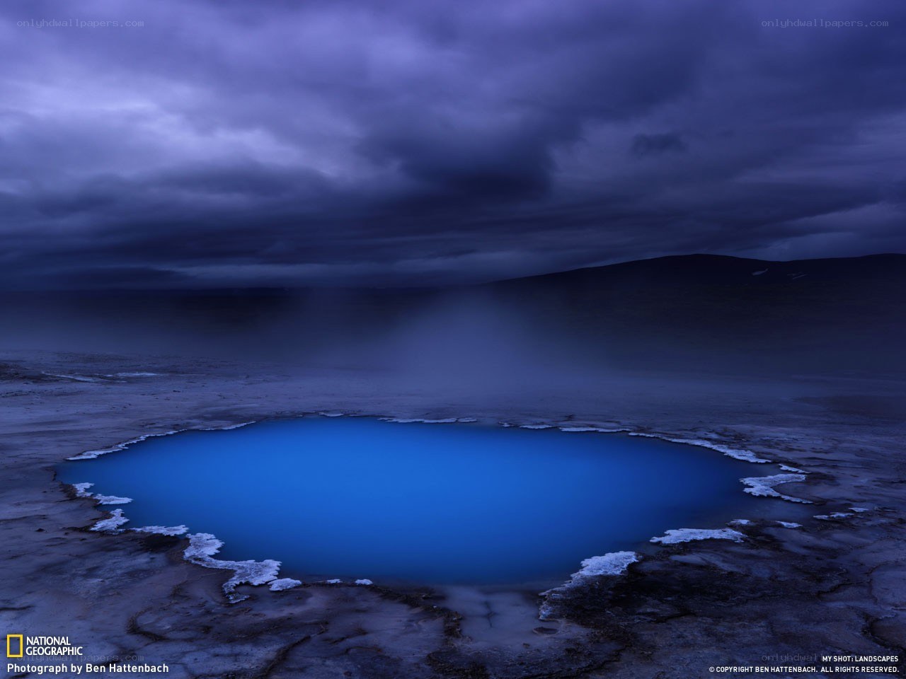Blue geothermal pool under stormy sky