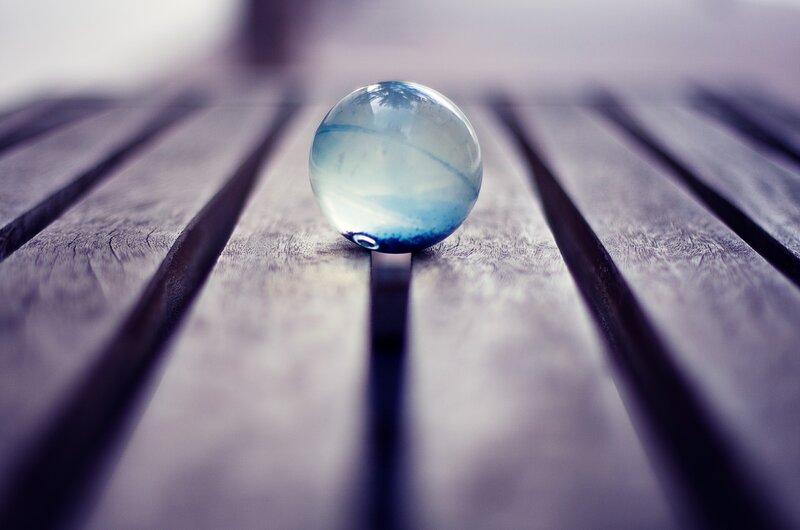 Blue glass marble on wood