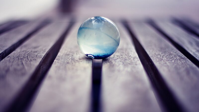 Blue glass marble on wood