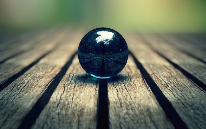 Blue glass marble on wood