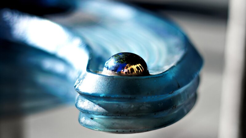 blue glass sculpture with water droplet