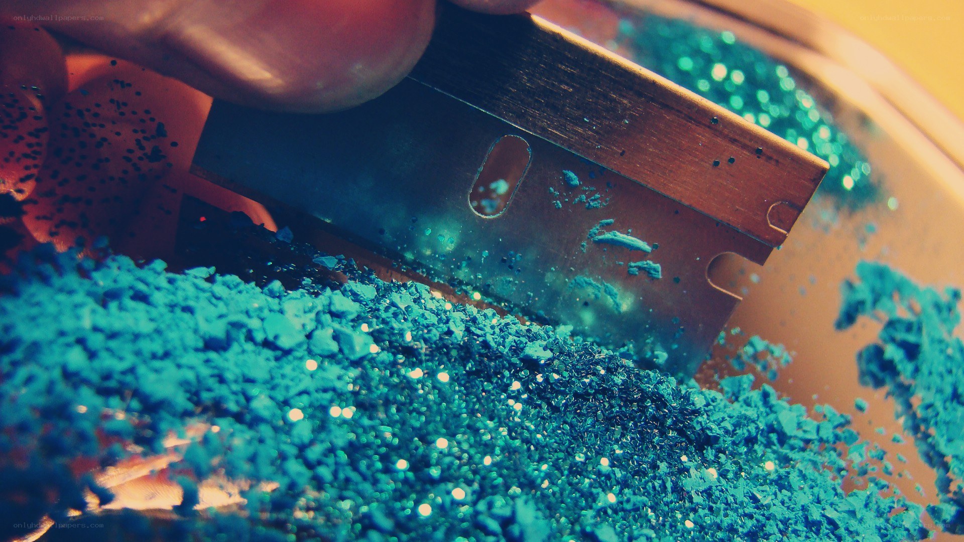 blue glitter being cut with a blade