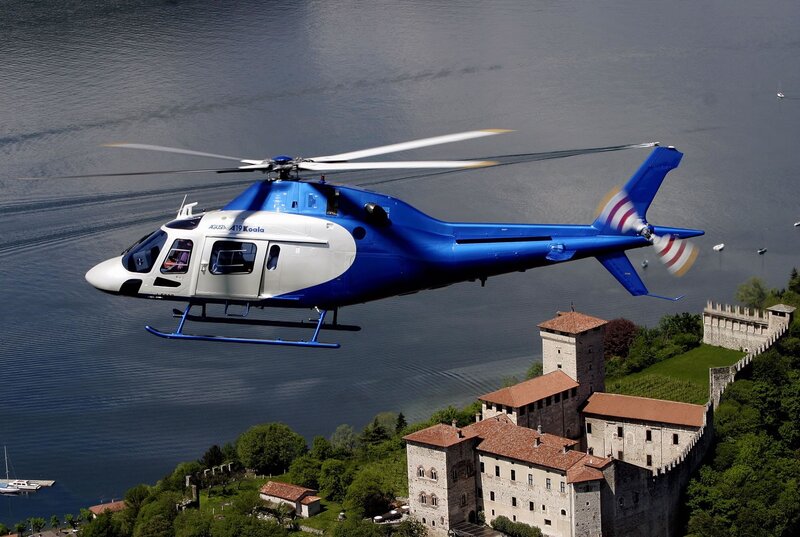 Blue helicopter over lake and castle