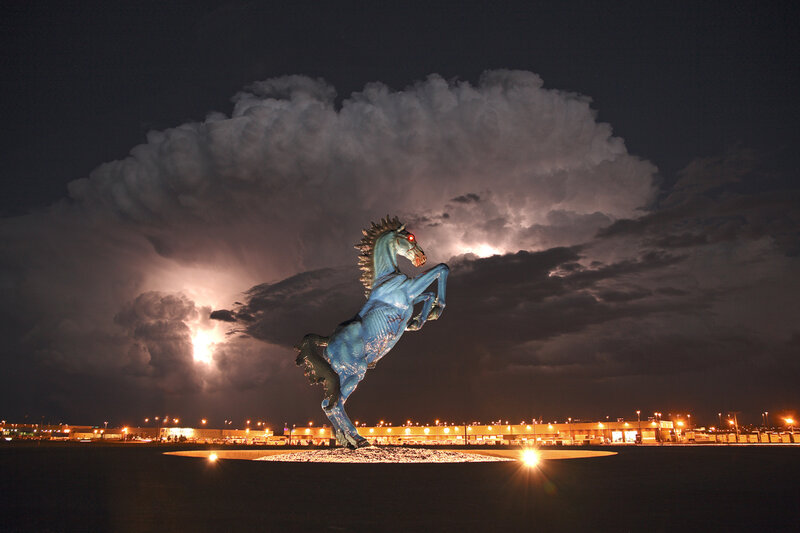 Blue horse statue under stormy sky