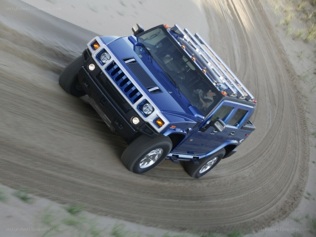 Blue Hummer driving on sand