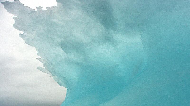 blue iceberg in cloudy sky