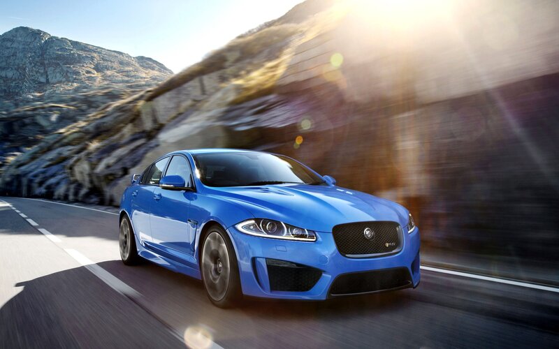 Blue Jaguar driving on mountain road