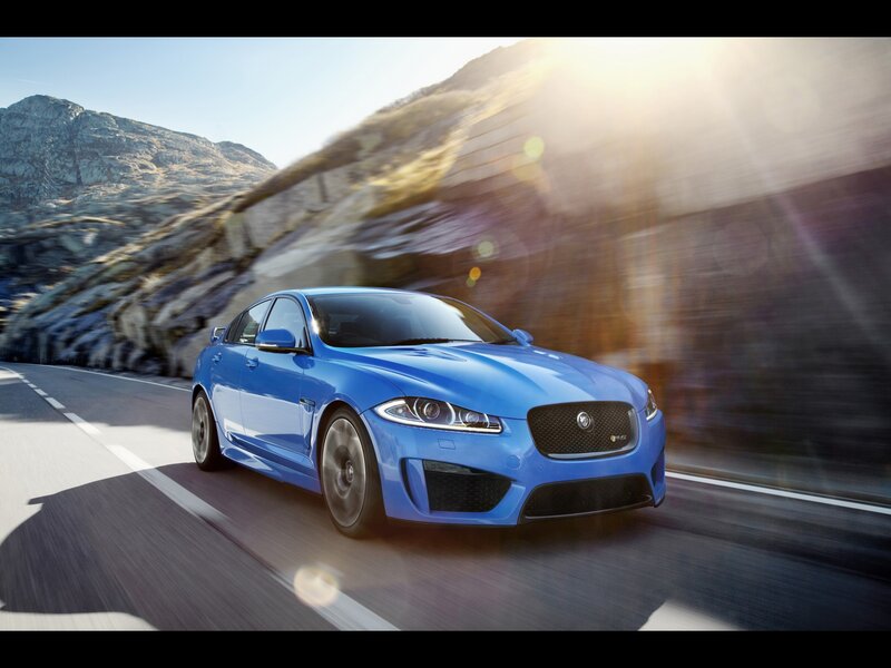 Blue Jaguar driving on mountain road
