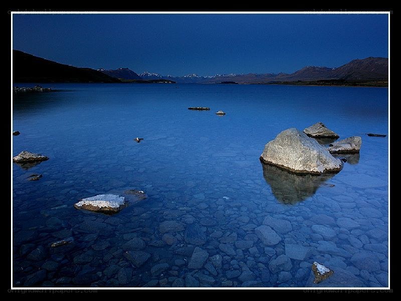 Blue lake at dusk with rocks