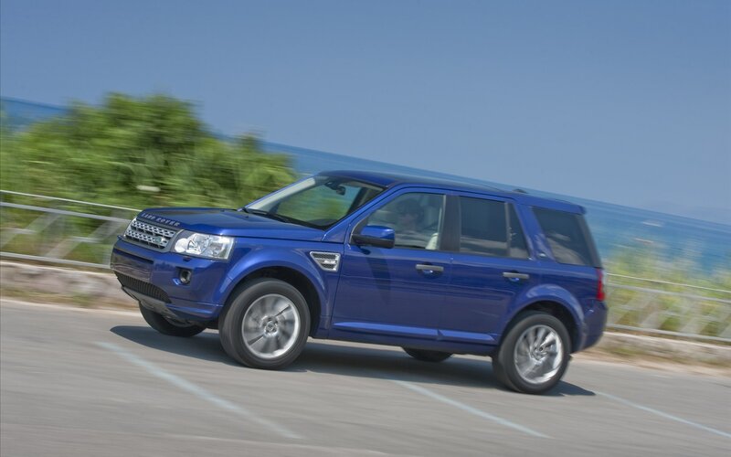Blue Land Rover driving on coastal road