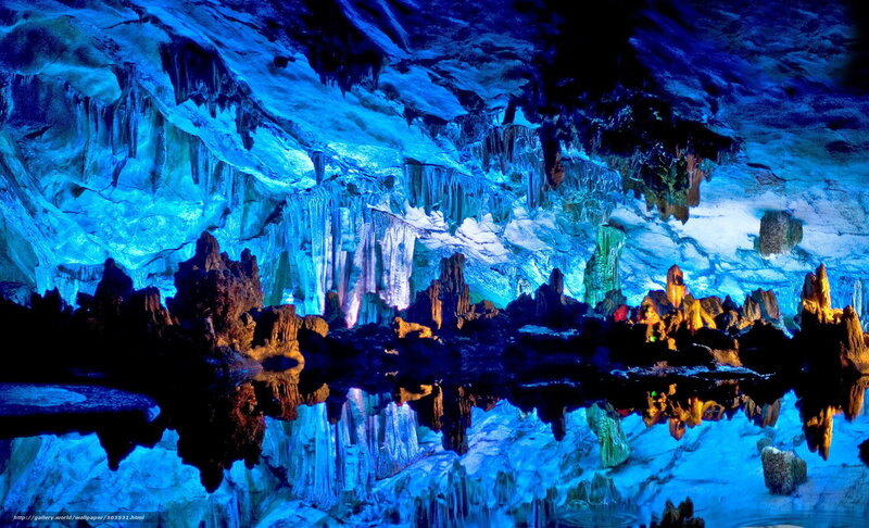 Blue-lit cave with stalactites and stalagmites
