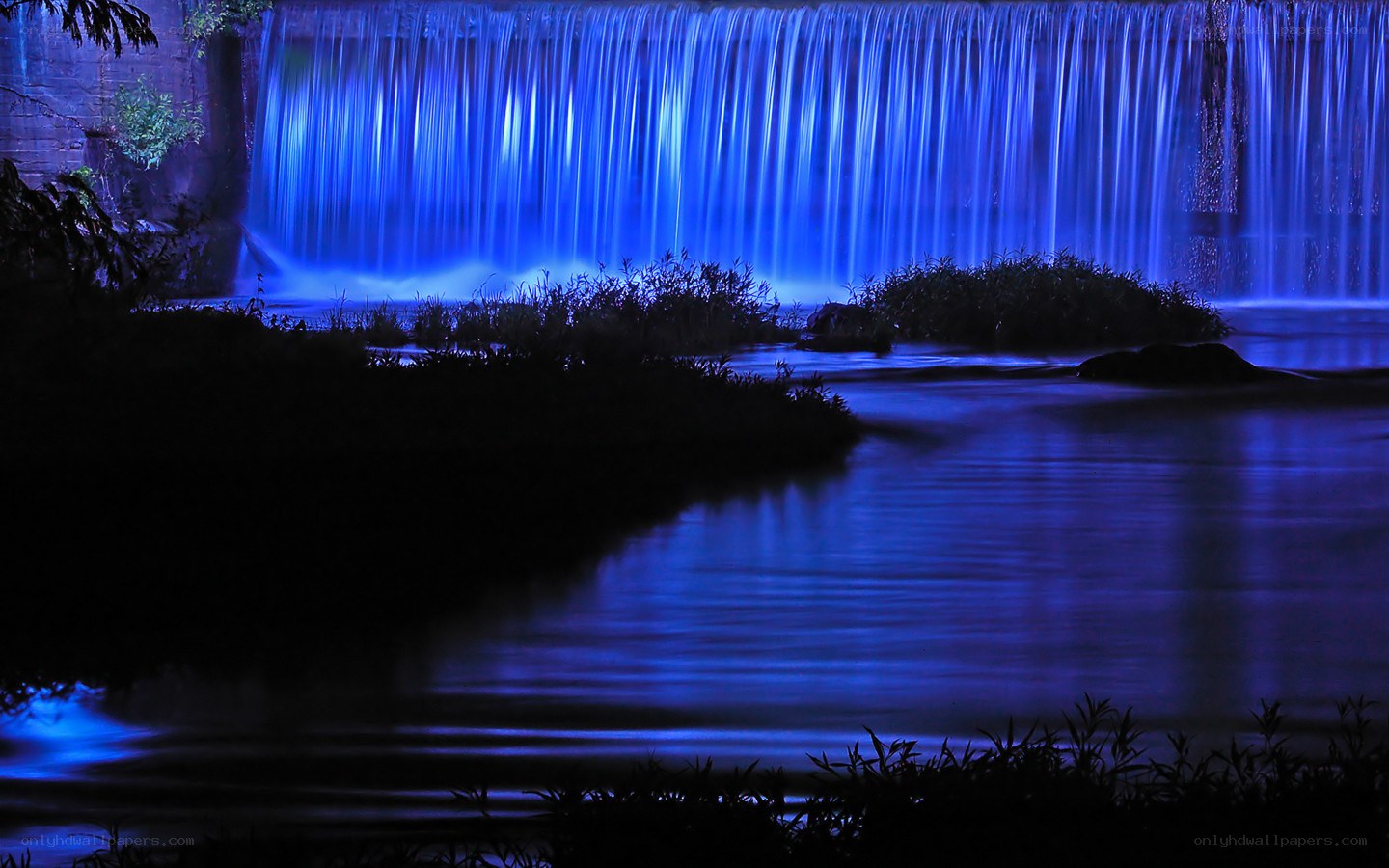 Blue-lit waterfall at night