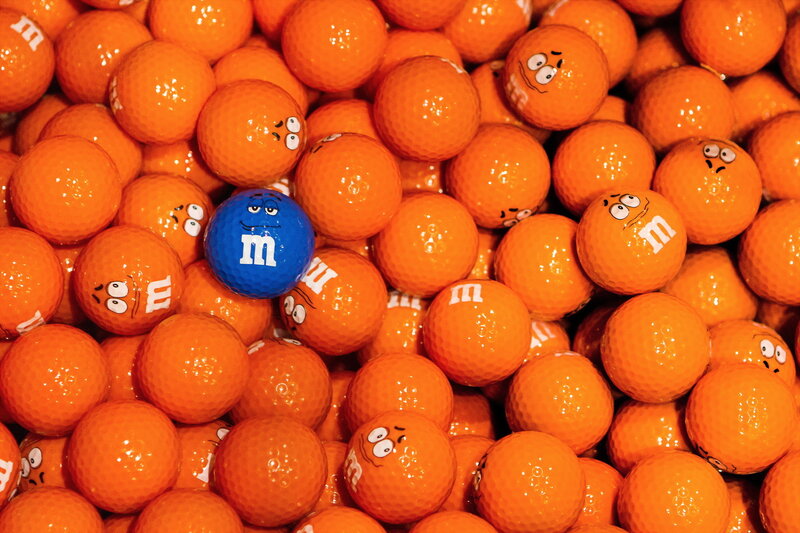 Blue M&M golf ball among orange ones