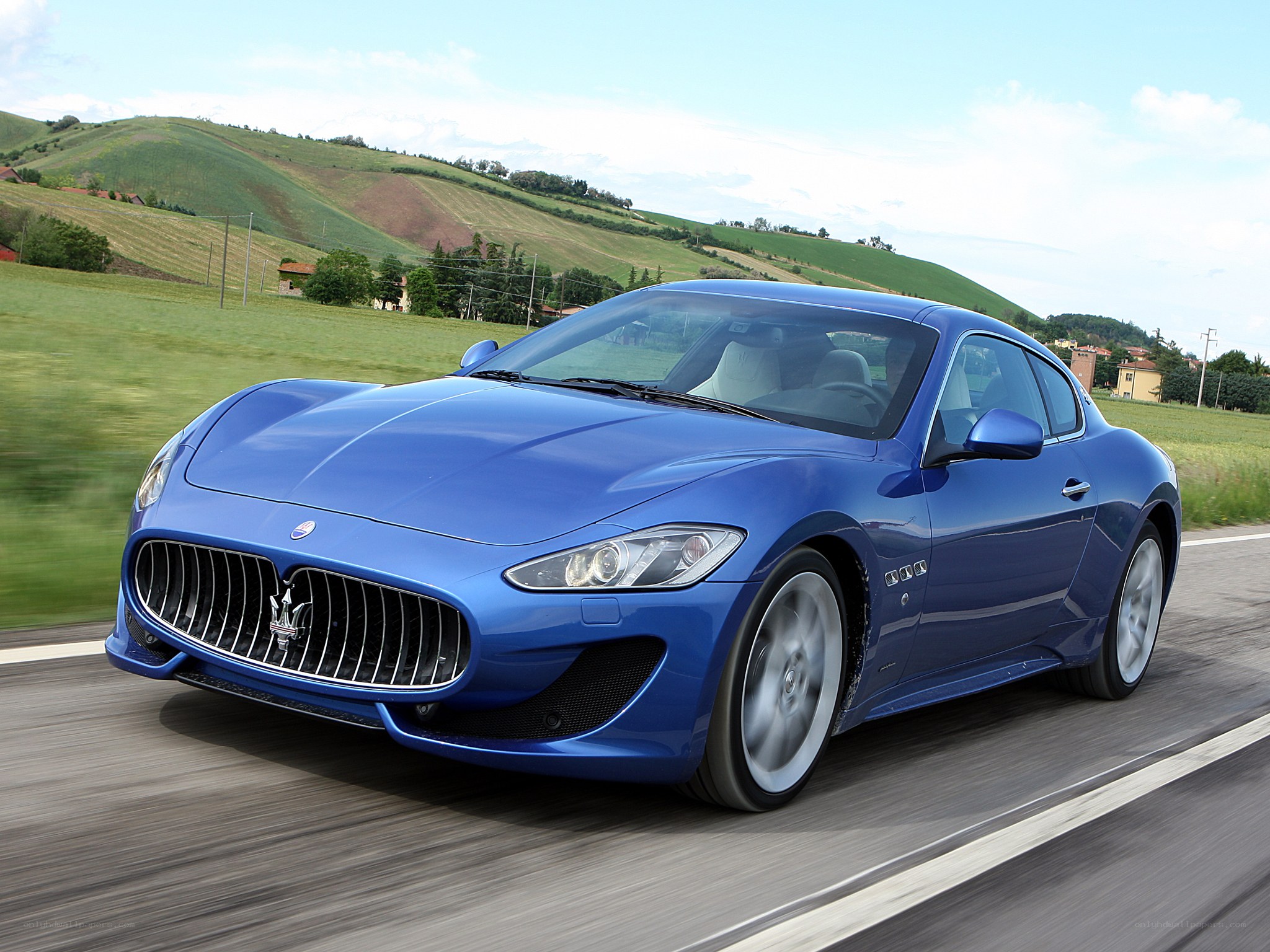 Blue Maserati driving on country road