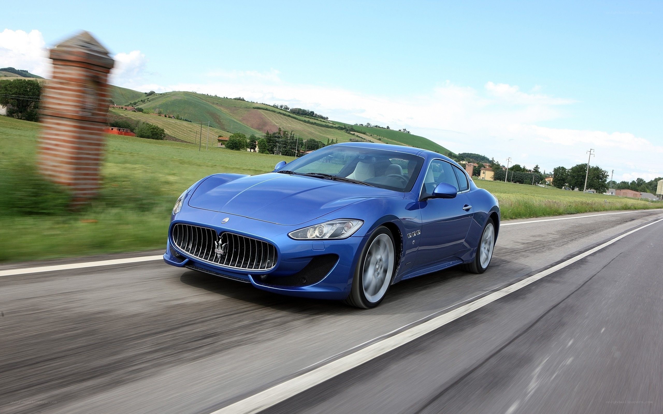 Blue Maserati driving on country road