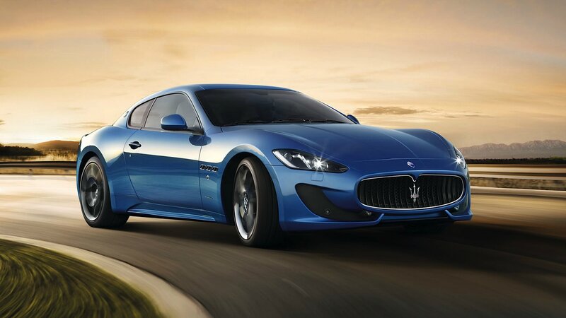 Blue Maserati driving on road