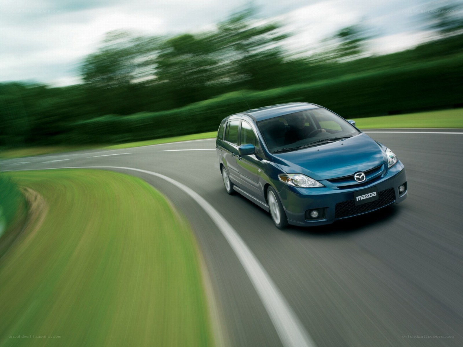 Blue Mazda MPV driving on a road