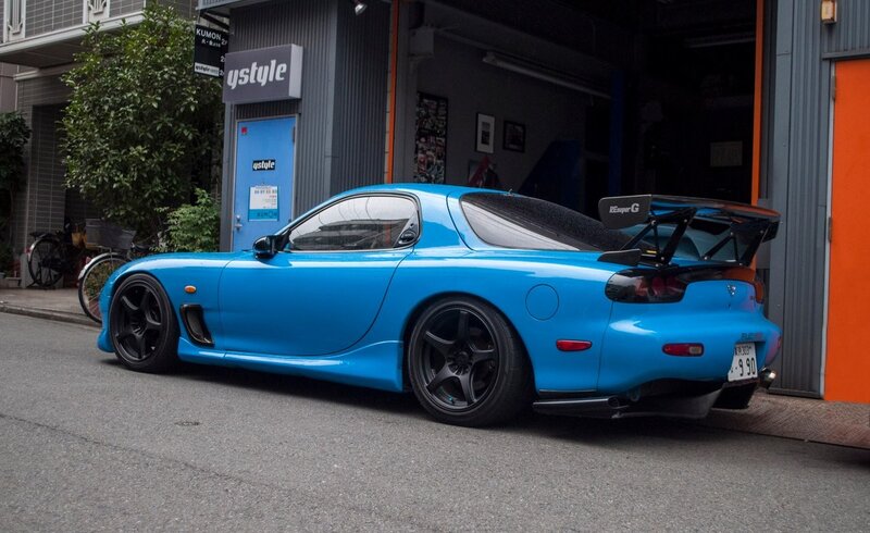 blue mazda rx-7 parked outside shop
