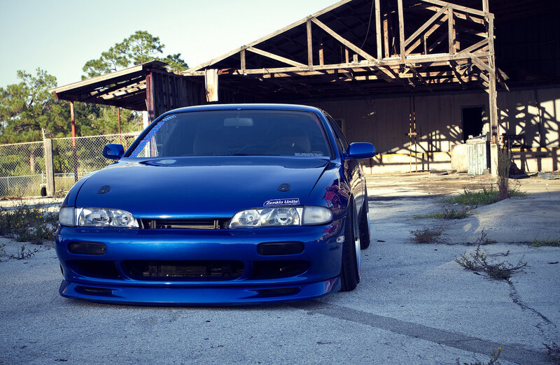 blue modified car in front of shed