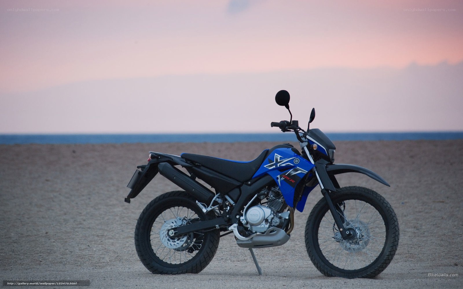 Blue motorcycle on beach at sunset
