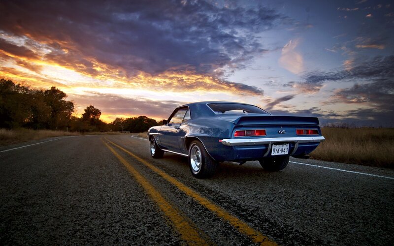 Blue muscle car on road at sunset
