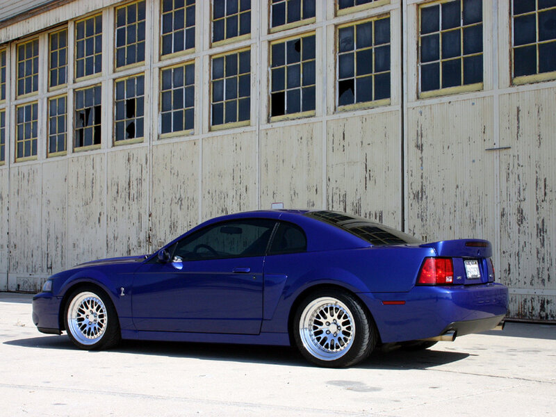 blue mustang in front of warehouse