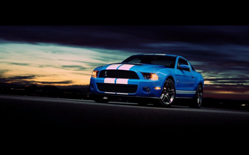 blue mustang on road at dusk