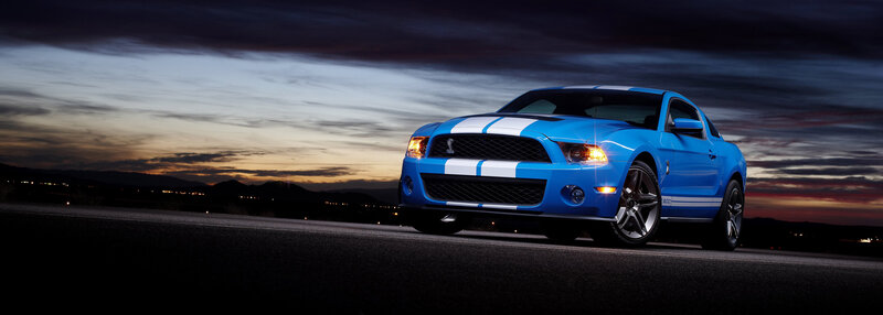 blue mustang on road at dusk