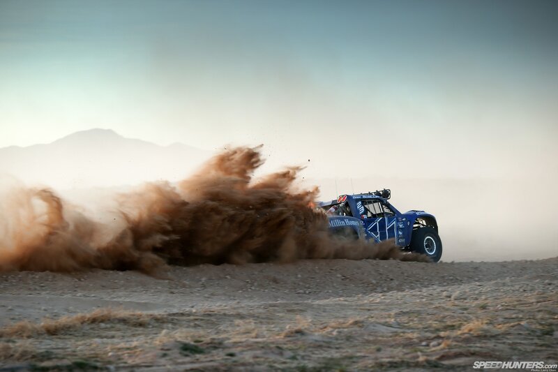 Blue off-road truck kicking up dust