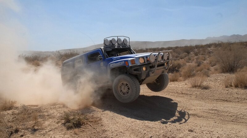 Blue off-road vehicle racing in desert