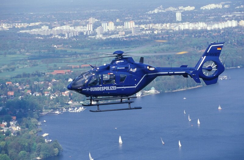 Blue police helicopter over lake