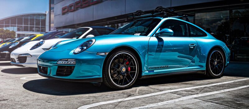 Blue Porsche Carrera parked outside dealership