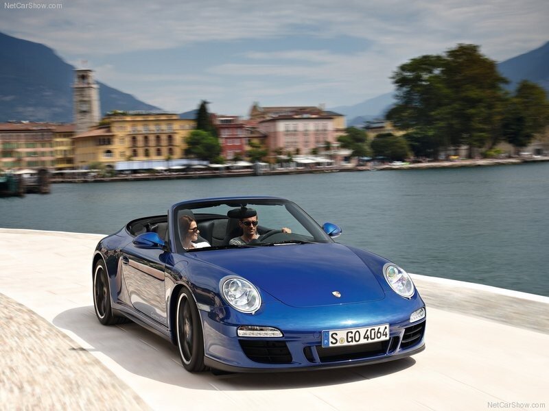 Blue Porsche convertible on a lakeside road